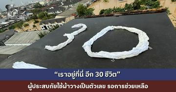 “เราอยู่ที่นี่ อีก 30 ชีวิต” ผู้ประสบภัยใช้ผ้าวางเป็นตัวเลขบนดาดฟ้า หวังได้รับการช่วยเหลือ